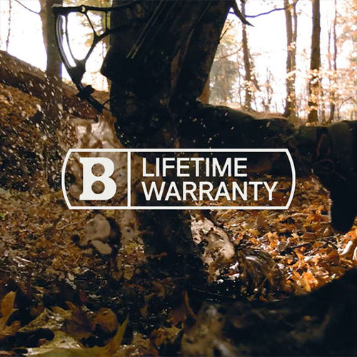 A close-up of a muddy bicycle tire splashing through fallen leaves in a forest, with the text B Lifetime Warranty in bold white letters overlaying the image.