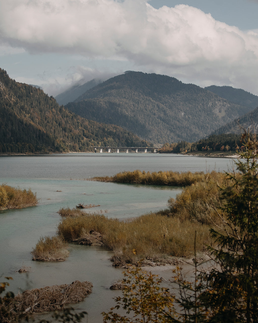 Scenic view of a lake with mountains and a bridge in the background