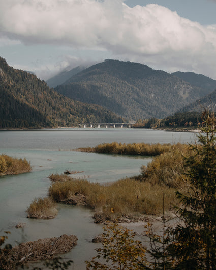 Scenic view of a lake with mountains and a bridge in the background