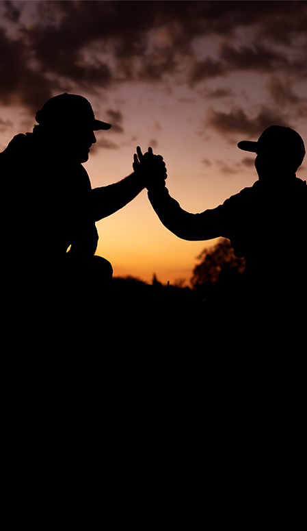 Two people giving each other a high-five against a sunset sky.