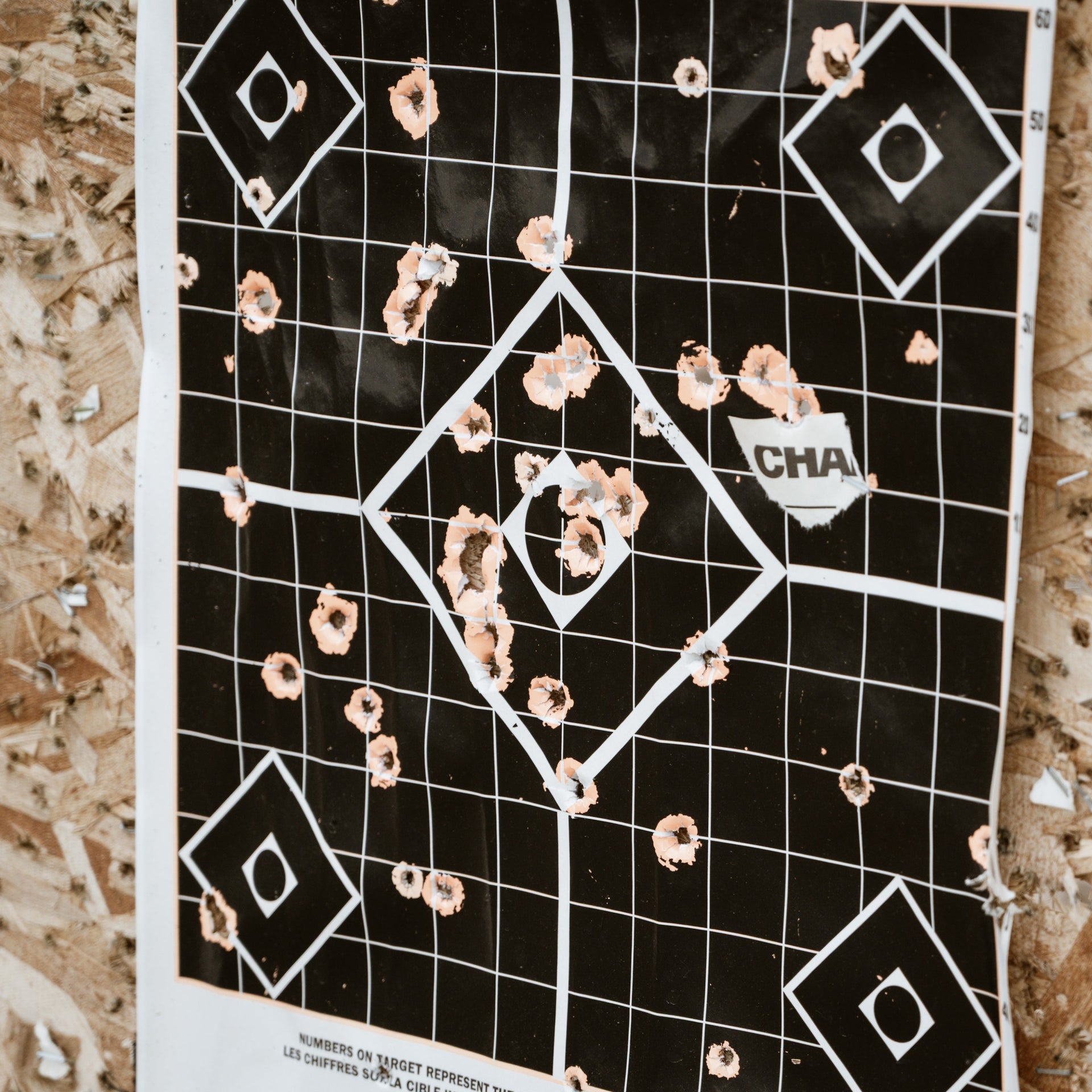 Black target with bullet holes on a wooden surface