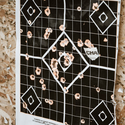 Black target with bullet holes on a wooden surface