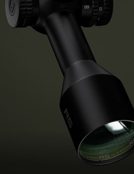 Close-up of a black optical scope with R5 and R-Series labeled on the lens housing, featuring adjustment dials, against a dark, blurred background.