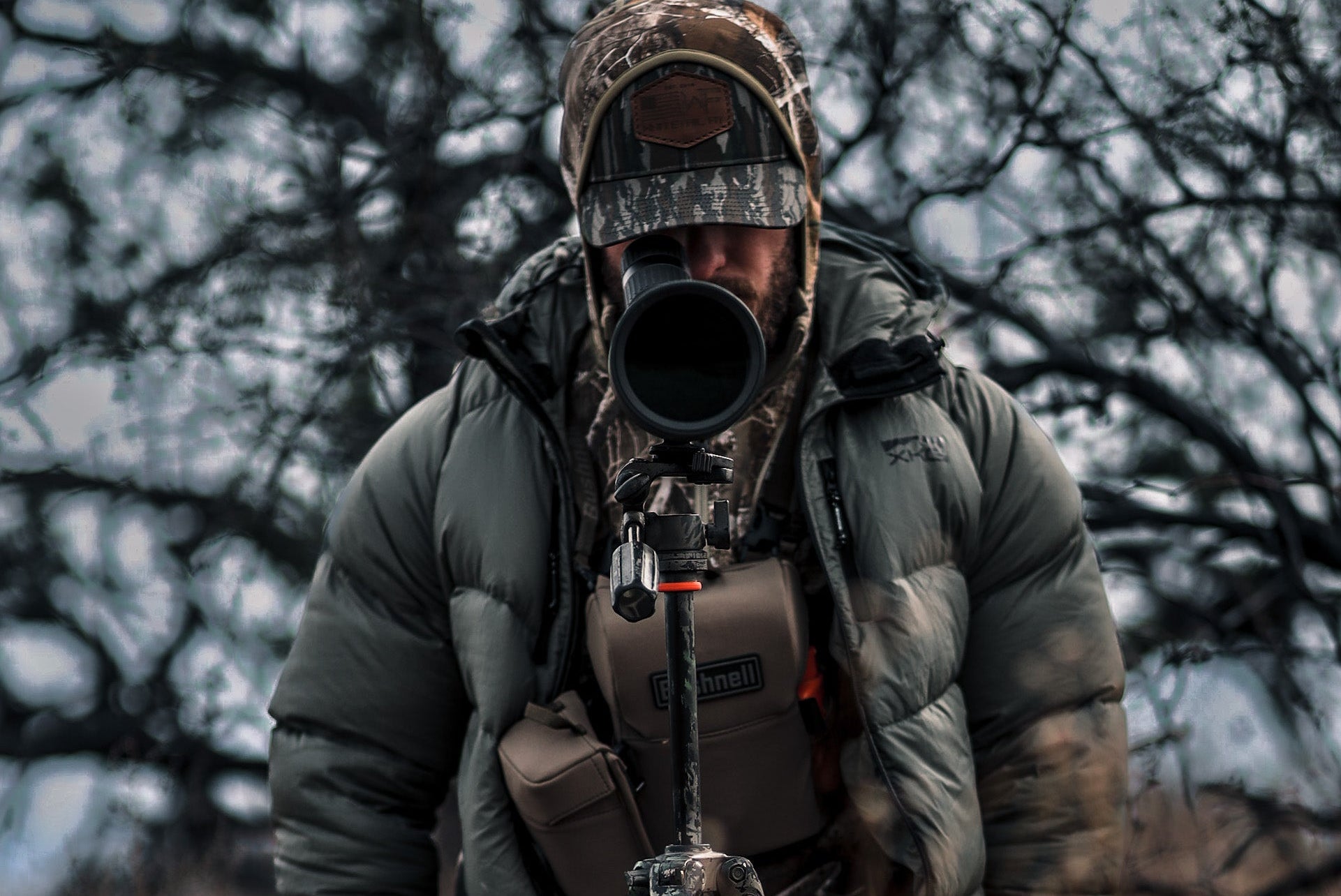 Person in camouflage gear with a large camera lens in a natural setting