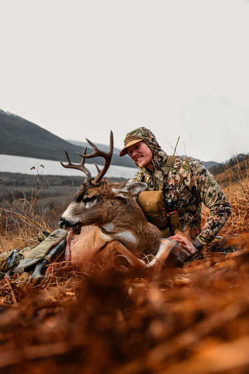 A man in camouflage with a deer.