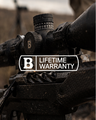 Close-up of a rifle scope with a 'B' brand lifetime warranty label.