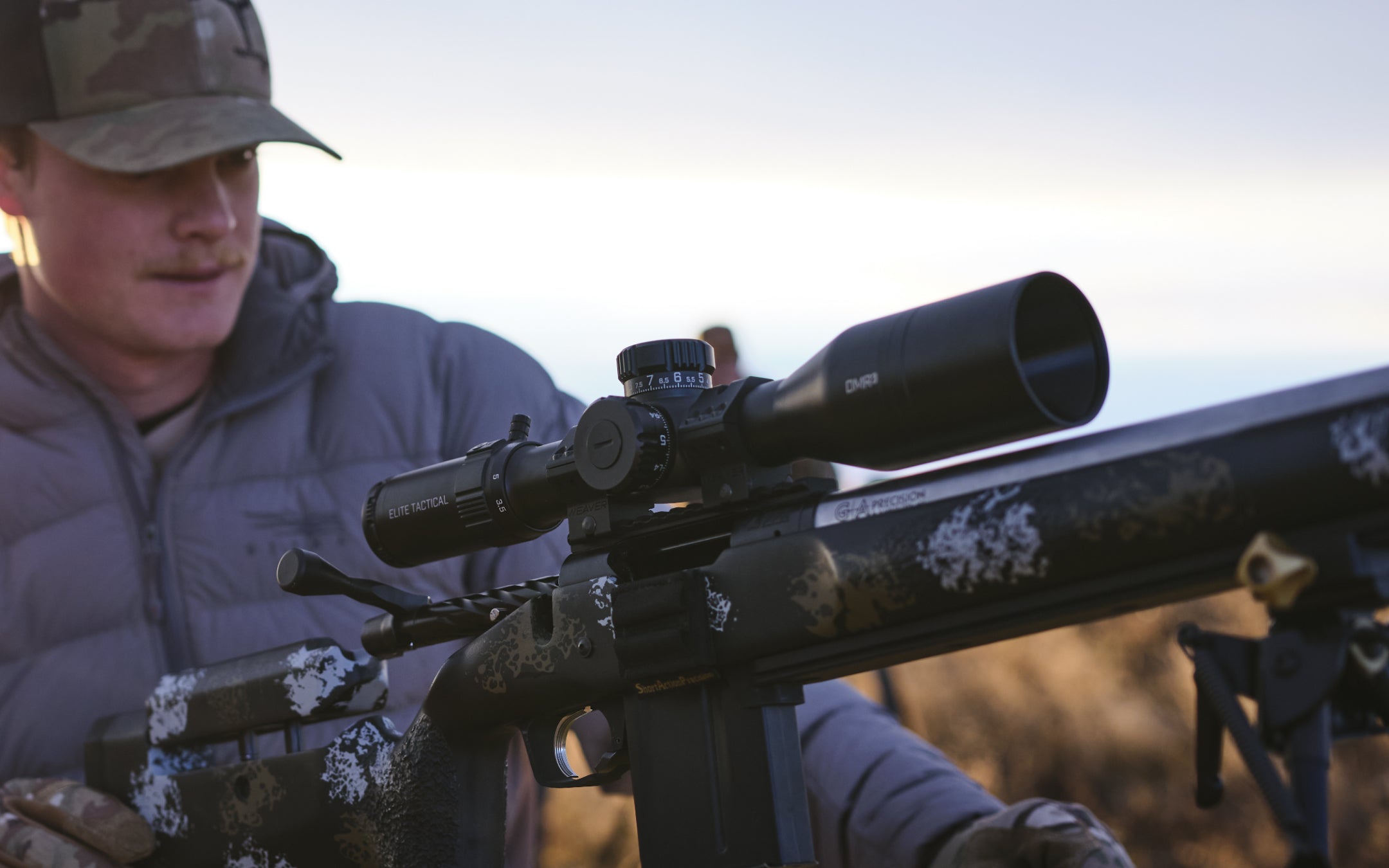 Person holding a rifle with a scope in an outdoor setting