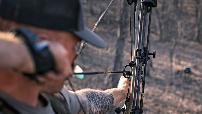 Over the shoulder view of bow hunter aiming bow from an elevated position