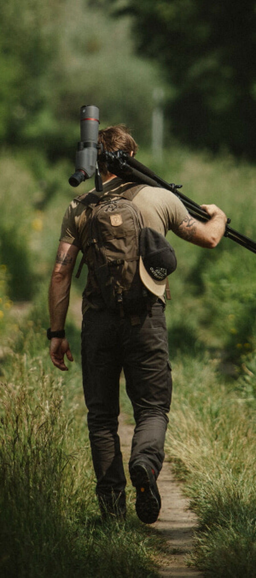 Man walking a trail carrying a Bushnell Spotting Scope