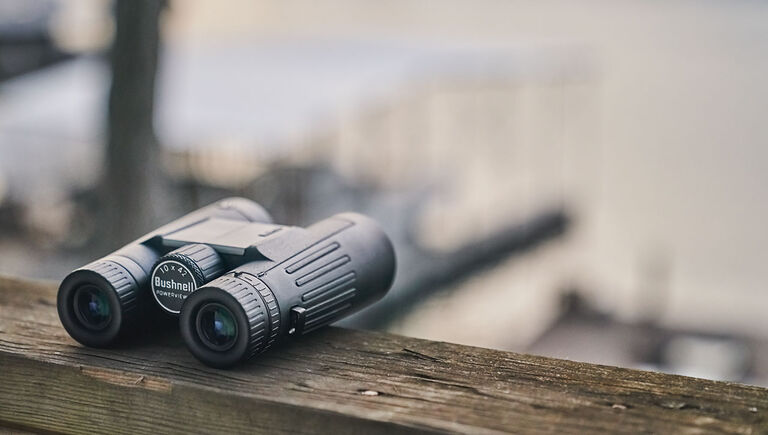 Binocolo Bushnell Powerview 2 seduto su una ringhiera di legno sul lungomare