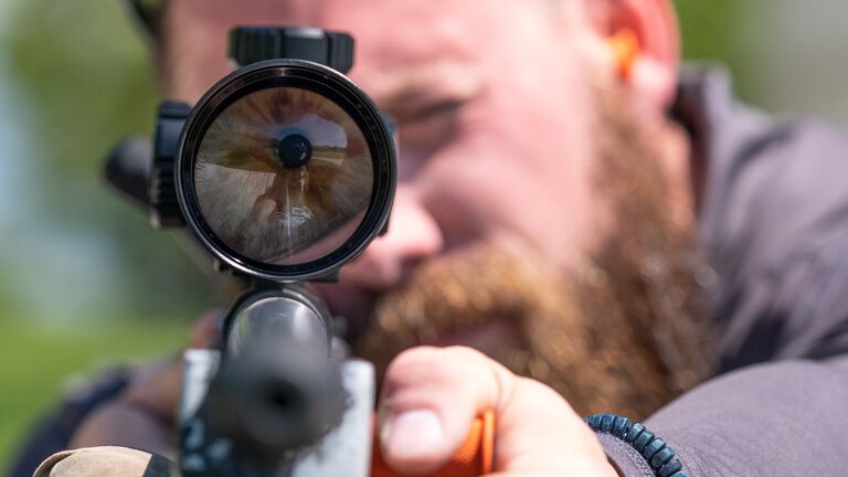 Man aiming through scope.