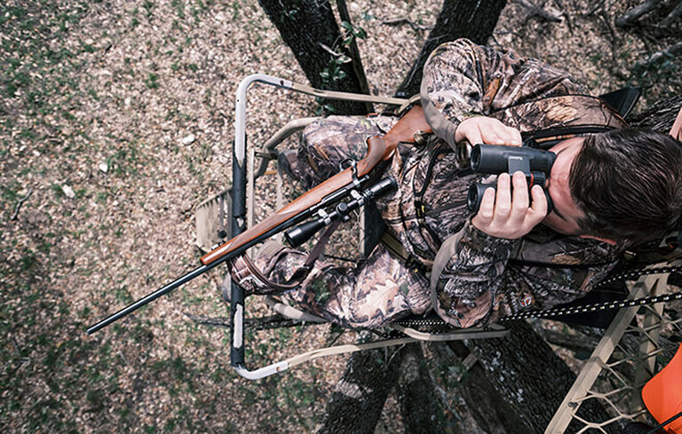 Hunter in tree stand looking through Nitro Binoculars