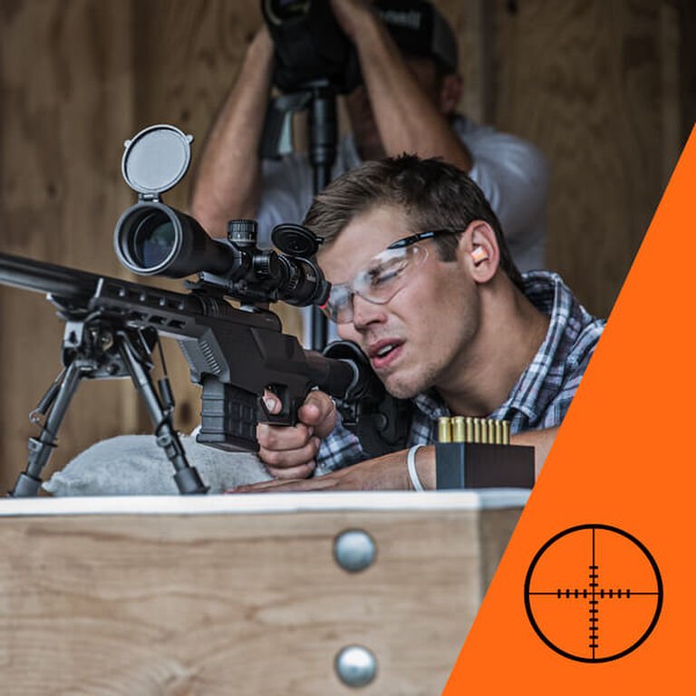 Target shooter aiming through riflescope with graduated reticle