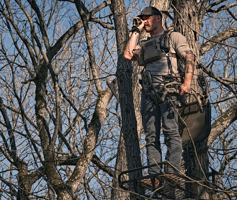 Hunter, in tree stand, looking through Broadhead Laser Rangefinder