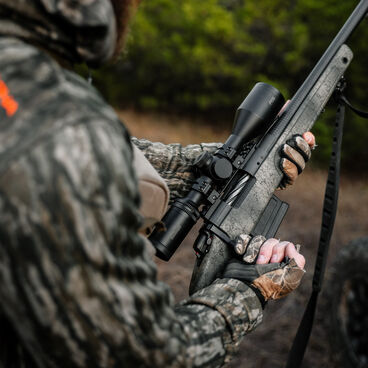 Man using a hunting rifle with a Bushnell riflescope Man using a hunting rifle with a Bushnell riflescope
