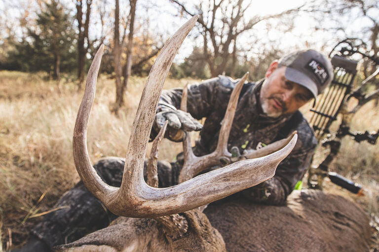 Bone Collector Michael Waddell inspecting a deer rack