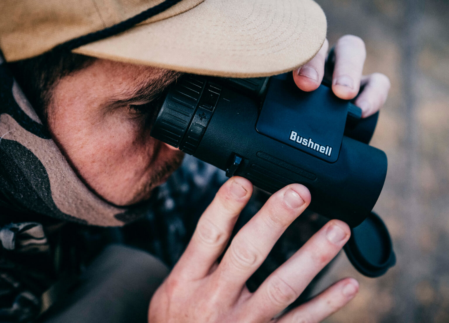 Close-up of man in the woods looking through Bushnell Binoculars