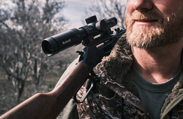 Hunter resting rifle over shoulder with Trophy Quick Acquisition Riflescope mounted on it