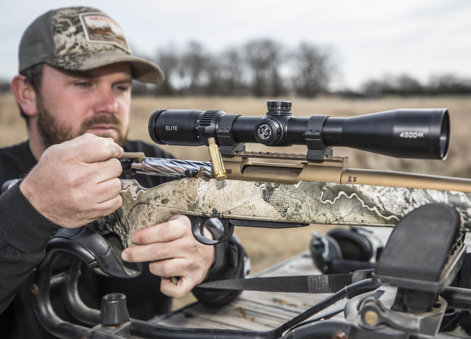 Hunter in a field sighting-in his rifle with a Bushnell Riflescope