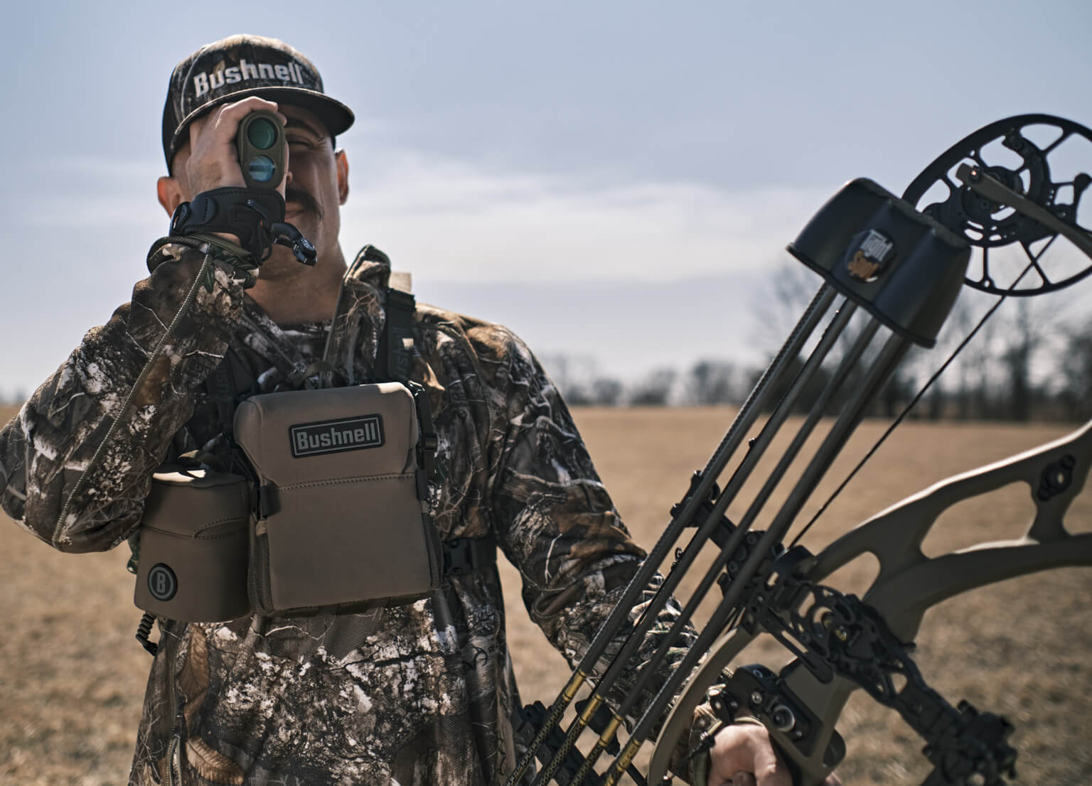 Hunter holding bow while looking through Broadhead Laser Rangefinder